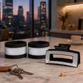 Two black VISIBLE reflective stroller bands, proportioned to the reflective hair claw, on a kitchen counter